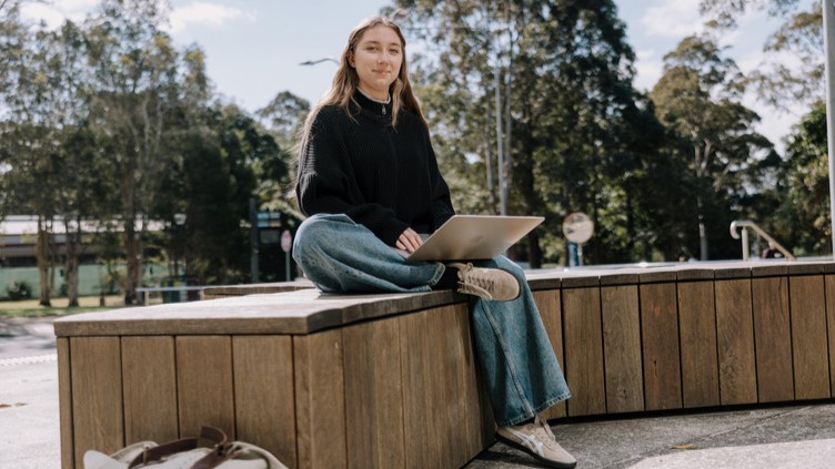 Student sitting outside with laptop on lap