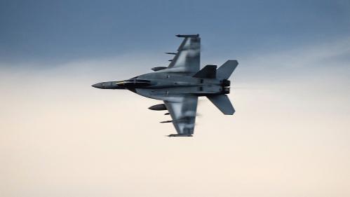 Fighter Jet flying side ways in a grey and light sky.