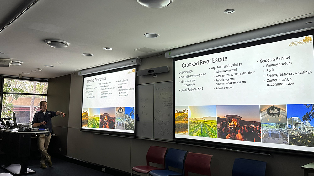 A presenter discusses Crooked River Estate, showcasing a slideshow with information on agri-tourism, services, and images of the venue.
