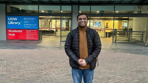 Kushagra, PhD BAL student stands outside the University of Wollongong Library entry
