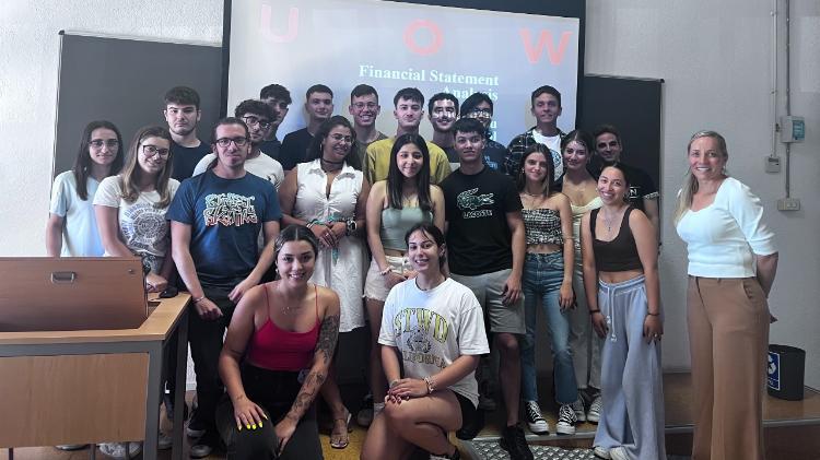 Tina Prodromou, a Lecturer with students in lecture room with a projector screen behind them.