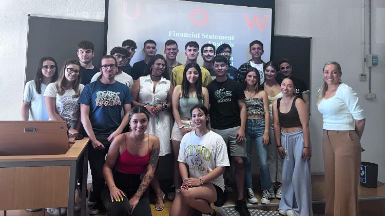 Tina Prodromou, a Lecturer with students in lecture room with a projector screen behind them.