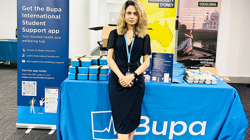 Woman stands at a stall table with Bupa items and branding displays.