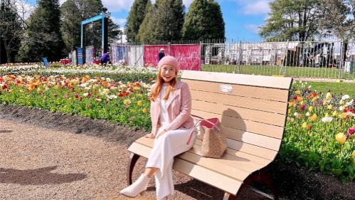 May Pyeetson Aung, Sydney Business School, UOW student, sits on a bench on a blue sky day.
