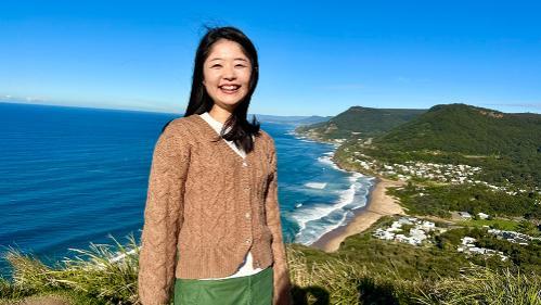 Sydney Business School, UOW Student, Sayaka Kobayashi  stands at outlook.