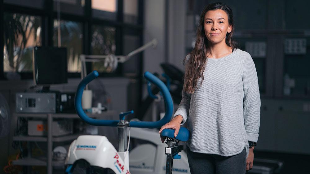 Grace Redden standing next to an exercise bike