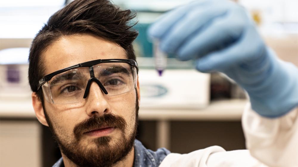 IHMRI researcher Jordan Cater holding a test tube