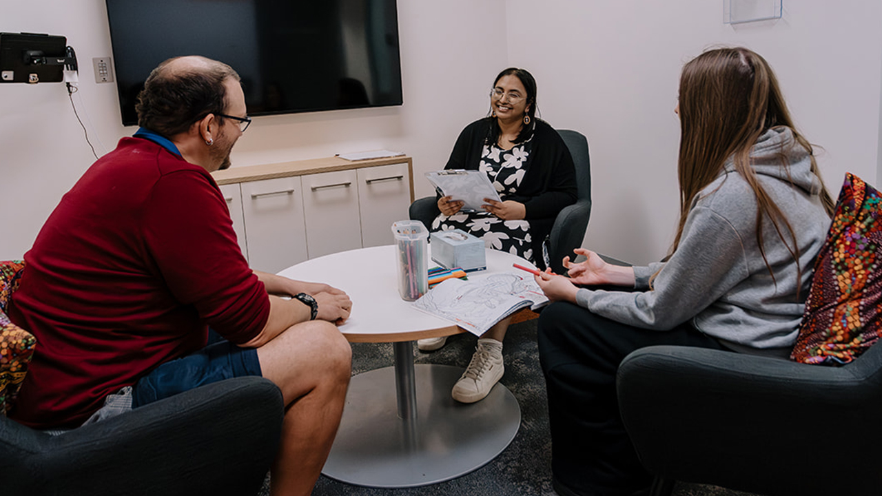 A researcher sits with a patient and her dad
