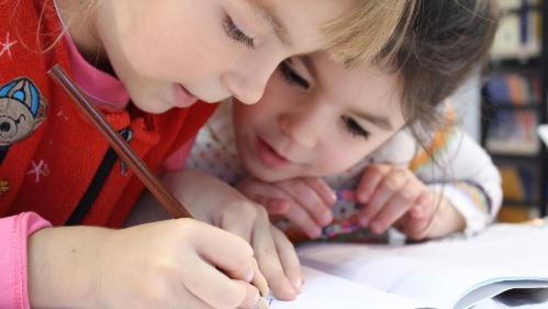 Two children sitting at a desk doing some bookwork