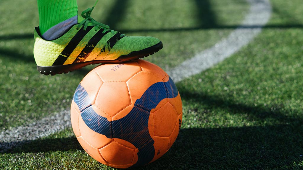 Booted foot resting on soccer ball