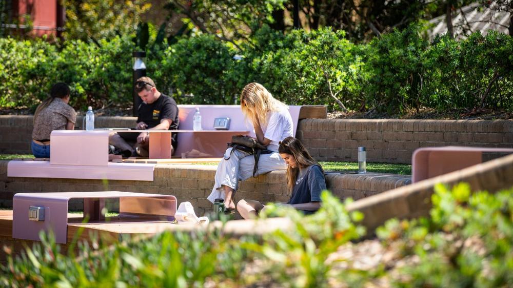 Students sitting in outdoor area out front of building 67