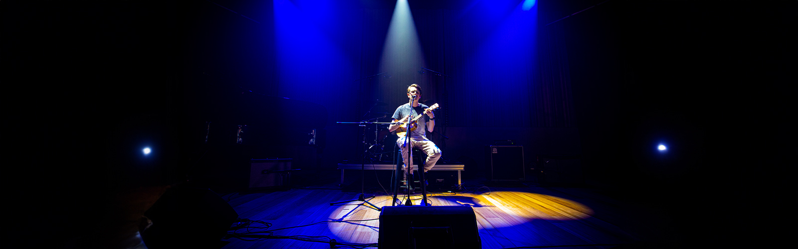 Male student sitting on a stool, centre stage