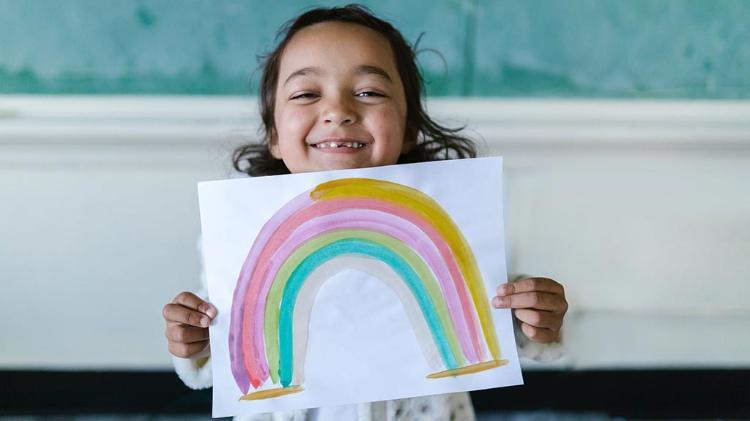 Female child proudly shows rainbow painting