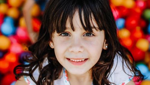 Young girl in ball pit smiling at camera