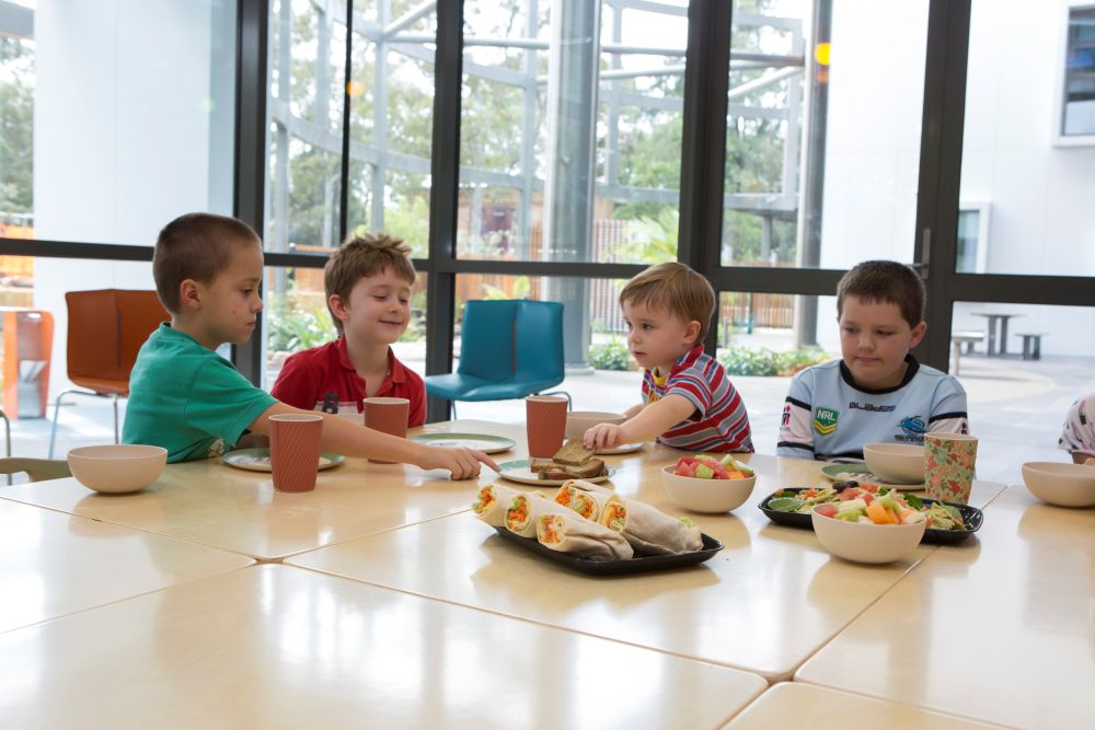 Children sit around a table at Early Start, eating healthy food