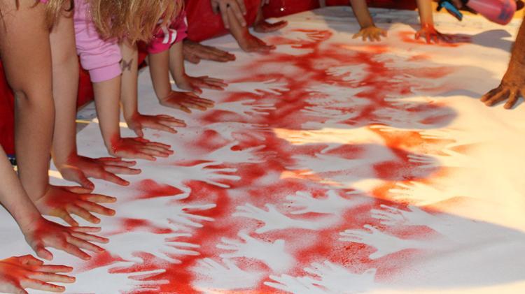 Hand Art. Multiple people have placed their hands on a big white piece of butchers paper, they have then painted over their hands to leave a vision of their hands silhouette