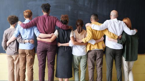 Photo from behind of educators standing in a row with their arms around eachother for support