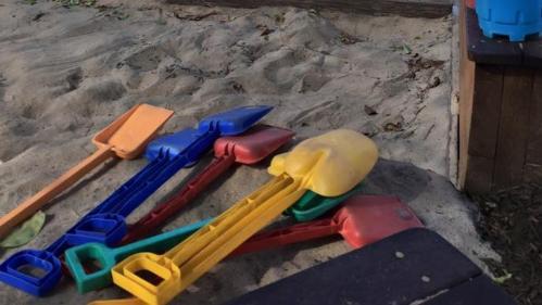 Multicoloured spades in a sandpit at a childcare centre