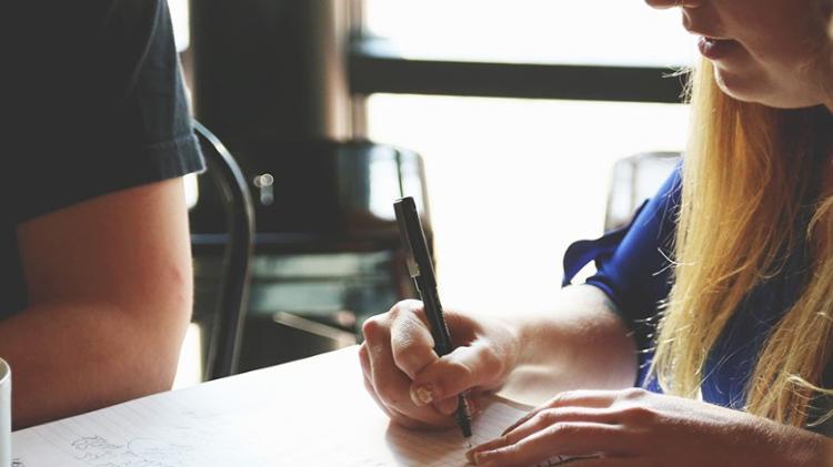 Lady writing in book while sitting at a table