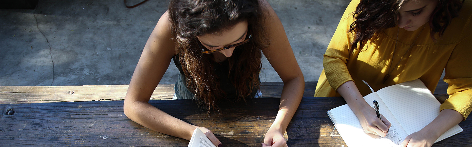 Two females reading on an outdoor table 