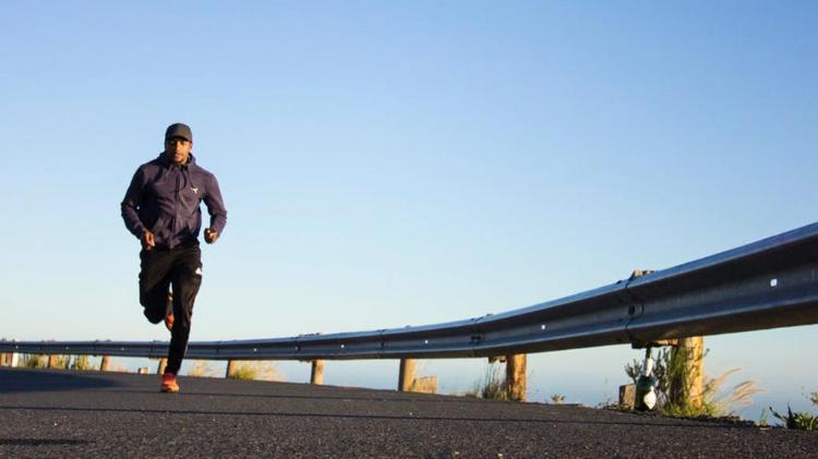 Man running on road with road barrier to his left hand side
