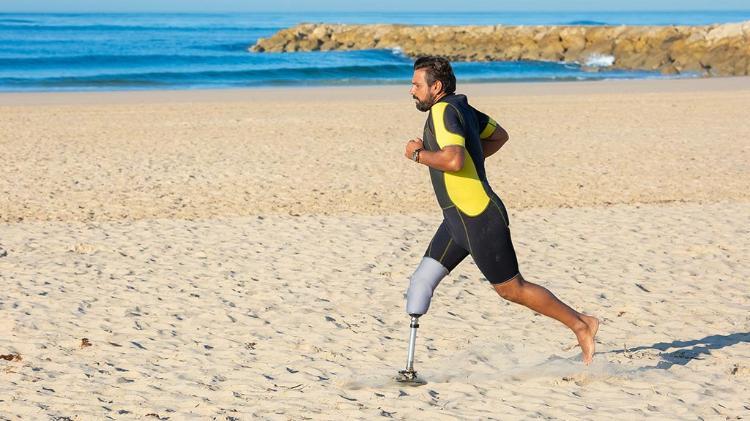 Man with prosthetic leg running on beach