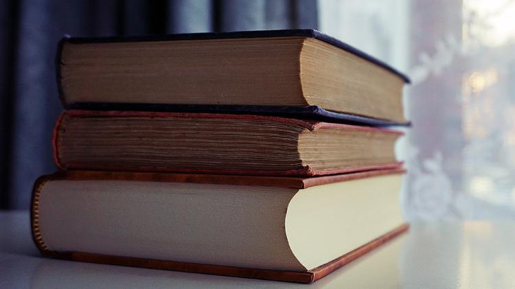 Three Piled Books on White Wooden Table