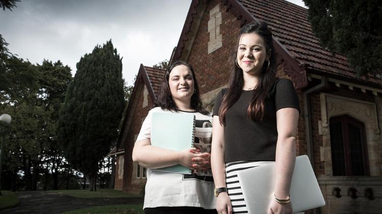 two students standing in front of an old church building