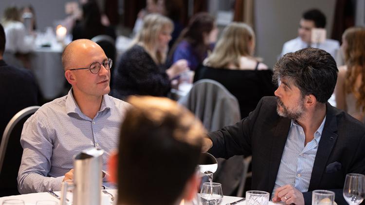 Two men sitting at table at a function