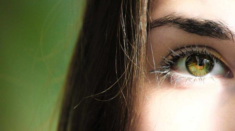 Eys shot of young lady standing on green background with green eye