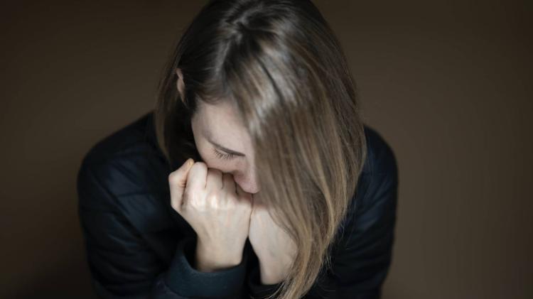 lady sitting at table with her head bowed and her hands in her face