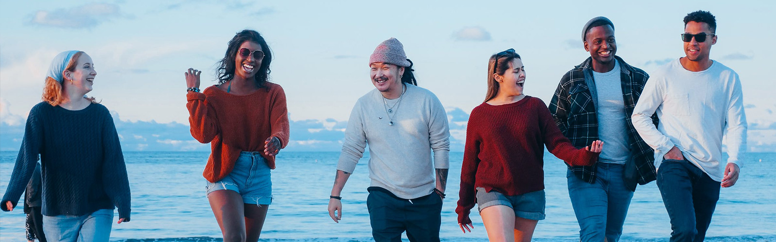Diverse group of young adults walking on beach