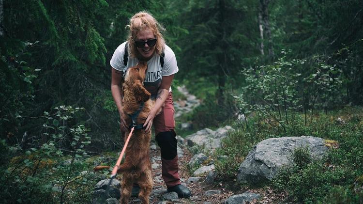 Lady hugging dog in bushes