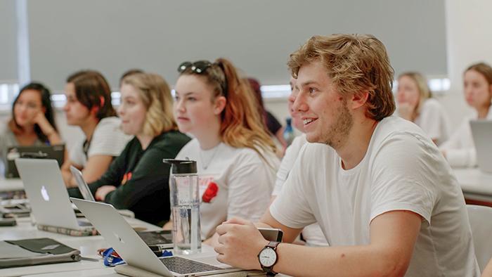 Writing and English students sitting at desks in classroom