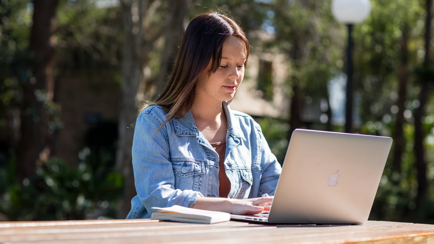 A person sitting outside at 51 Campus using a laptop