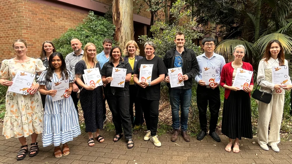 A group of people standing outdoors holding award certificate each.