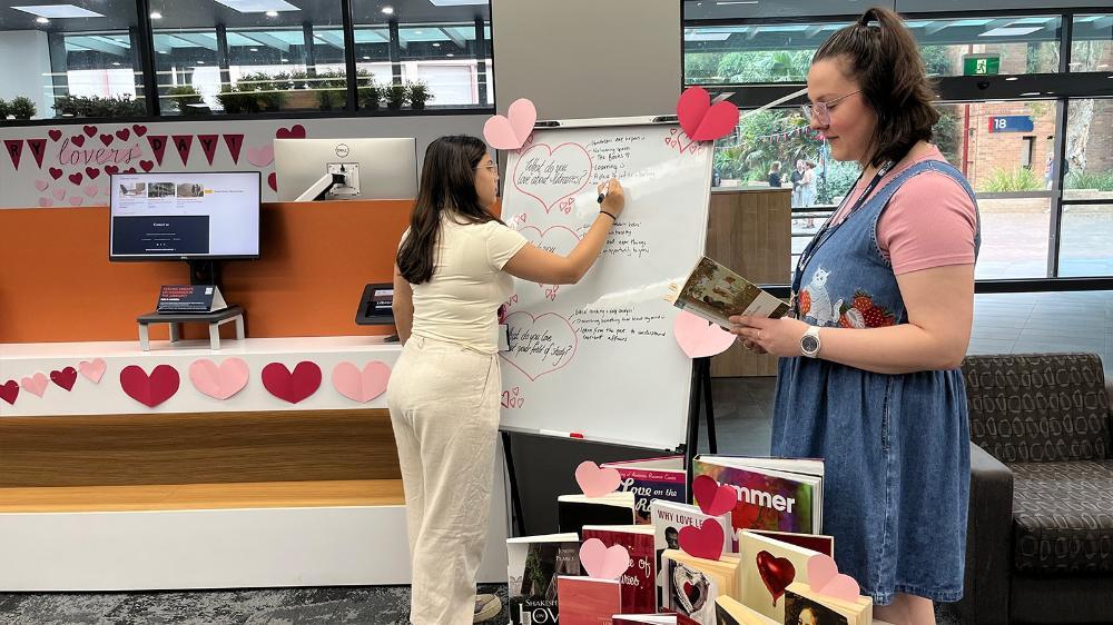 Library staff standing next to valentines day theme decorations and books