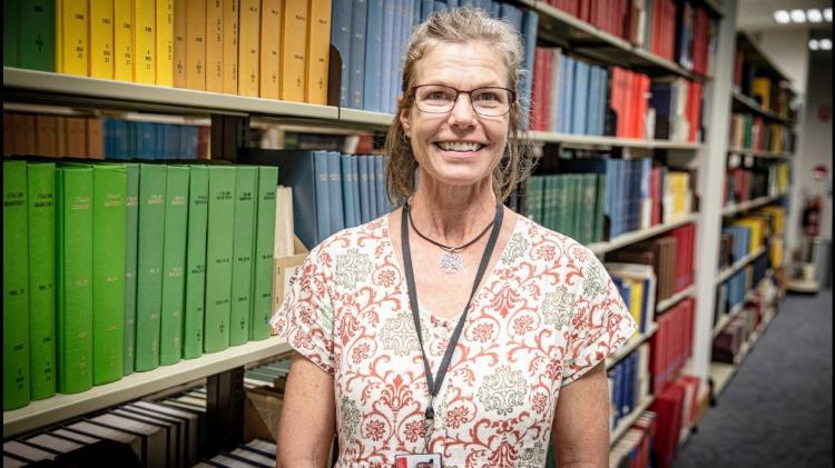 Library staff member smiling next to books