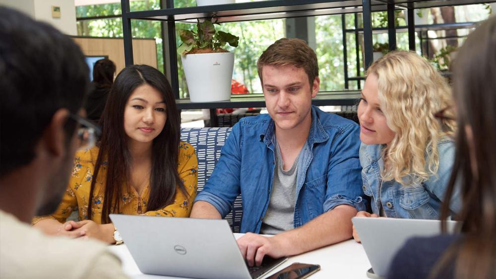 A group of students around a laptop in the Library