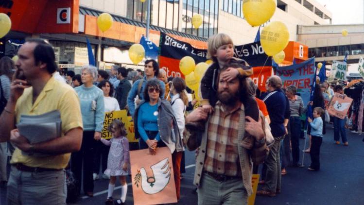 Group of people marching along street, holding posters.