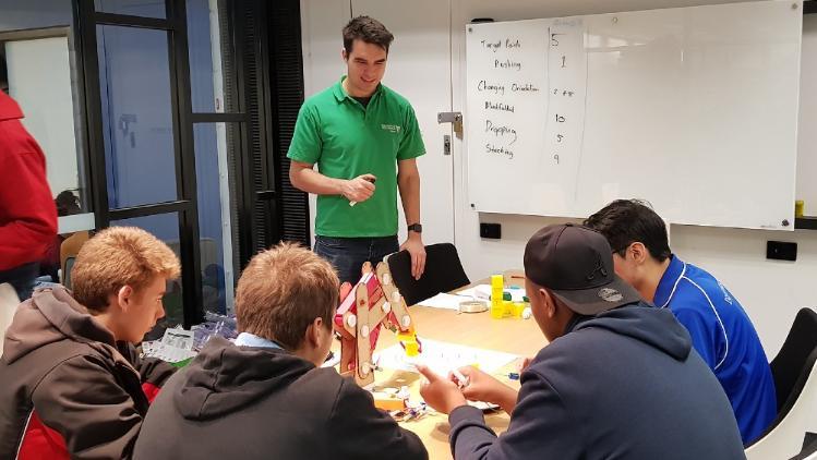 A student mentor facilitating a robotics workshop for four students