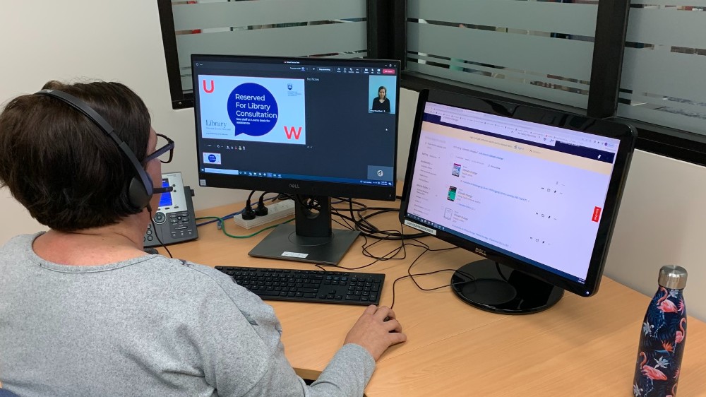 Staff member sitting at computer speaking with student via virtual service point