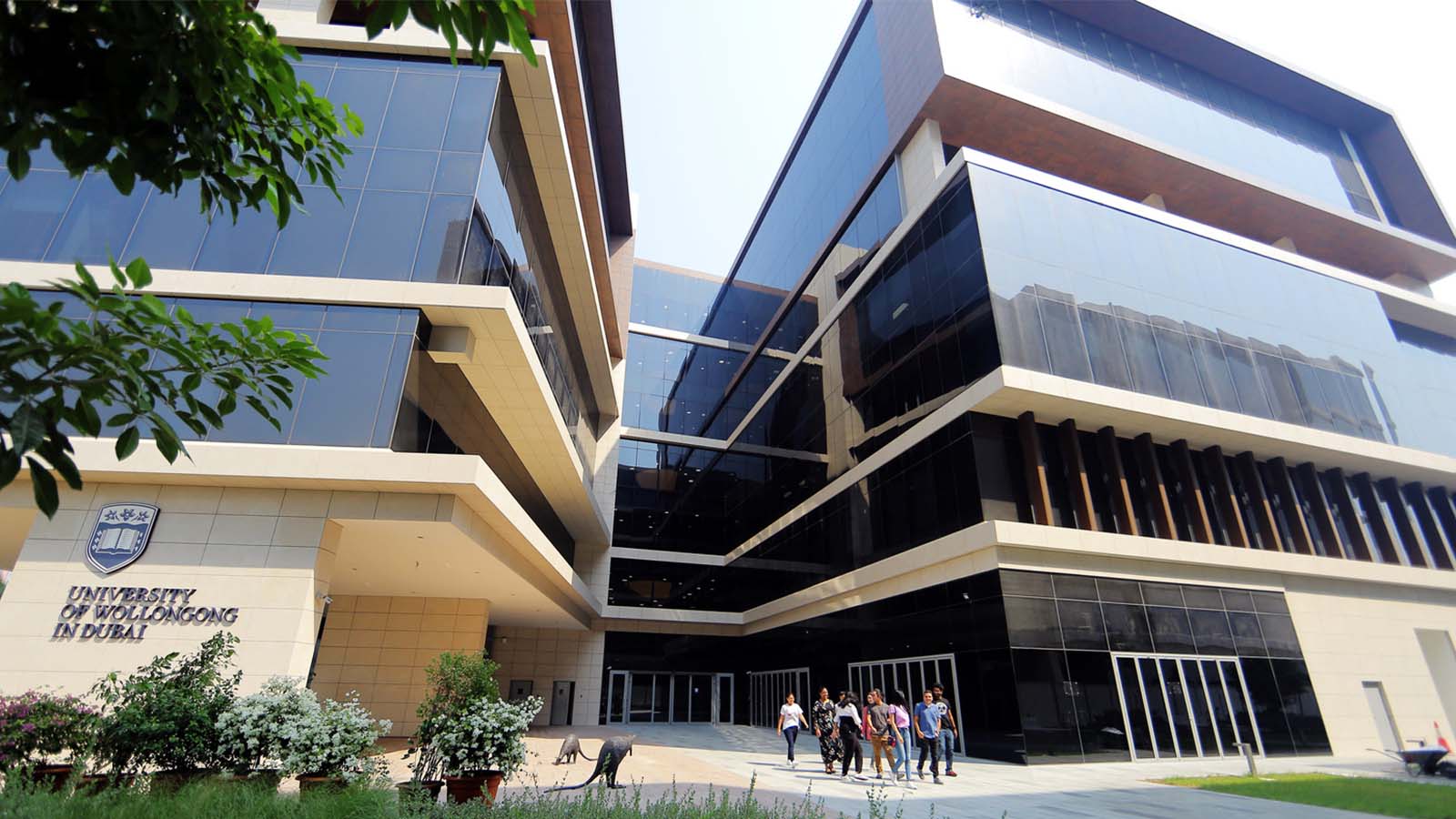 A group of students are walking out of a large building at UOW Dubai