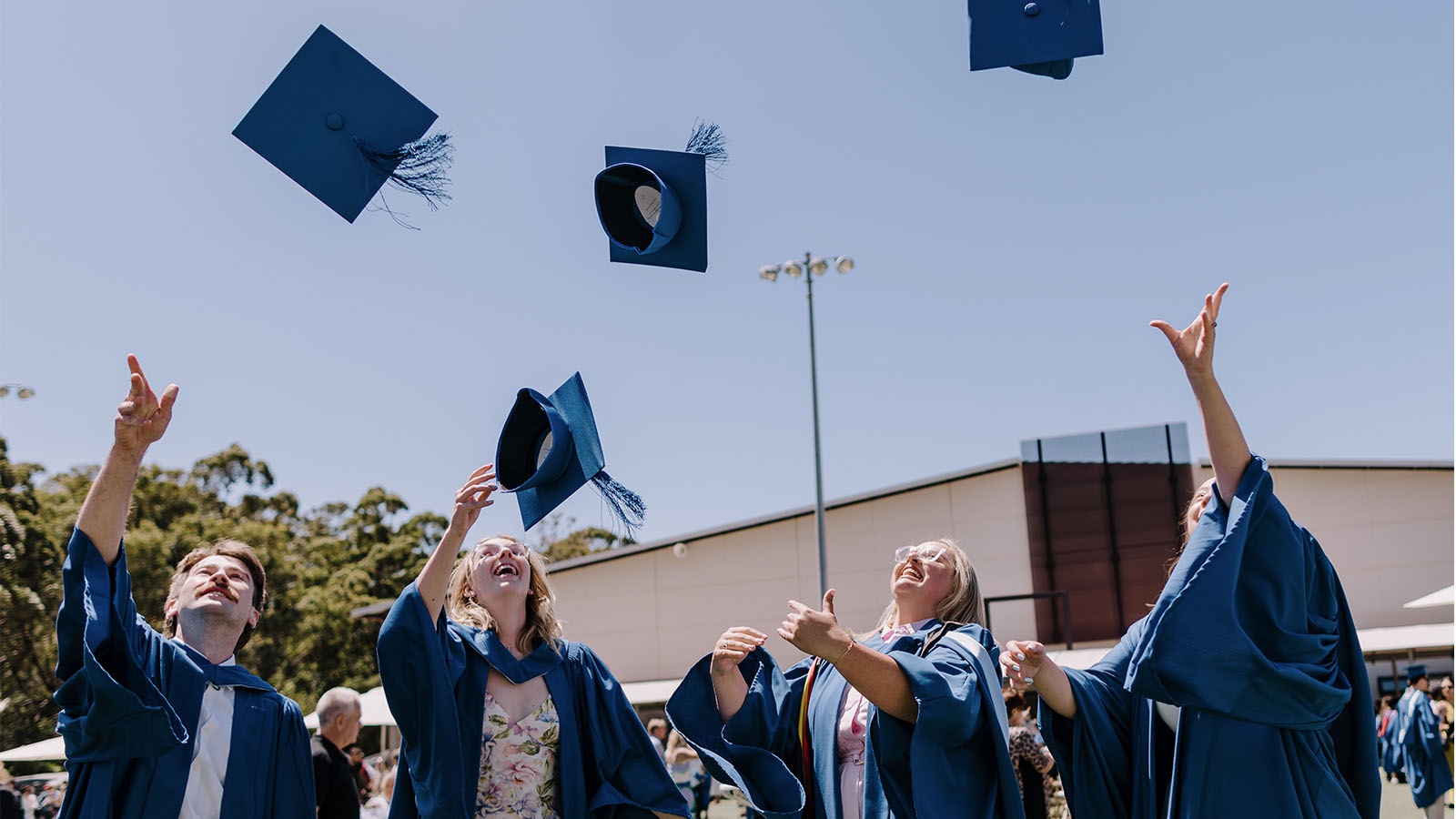A group of UOW graduates throwing their hats in the air