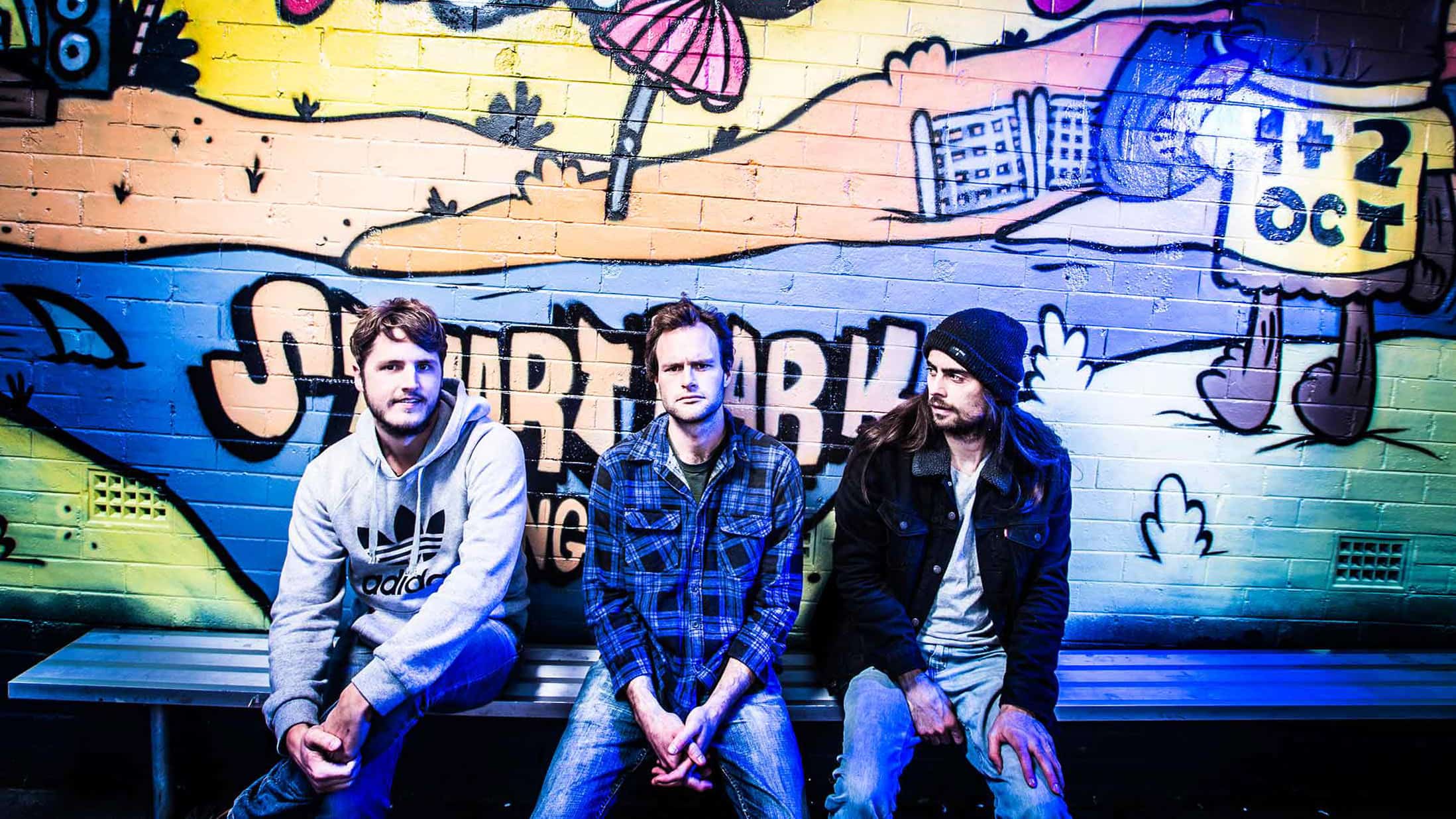 The team behind Yours and Owls sit in front of a graffiti covered wall. Photo: Paul Jones
