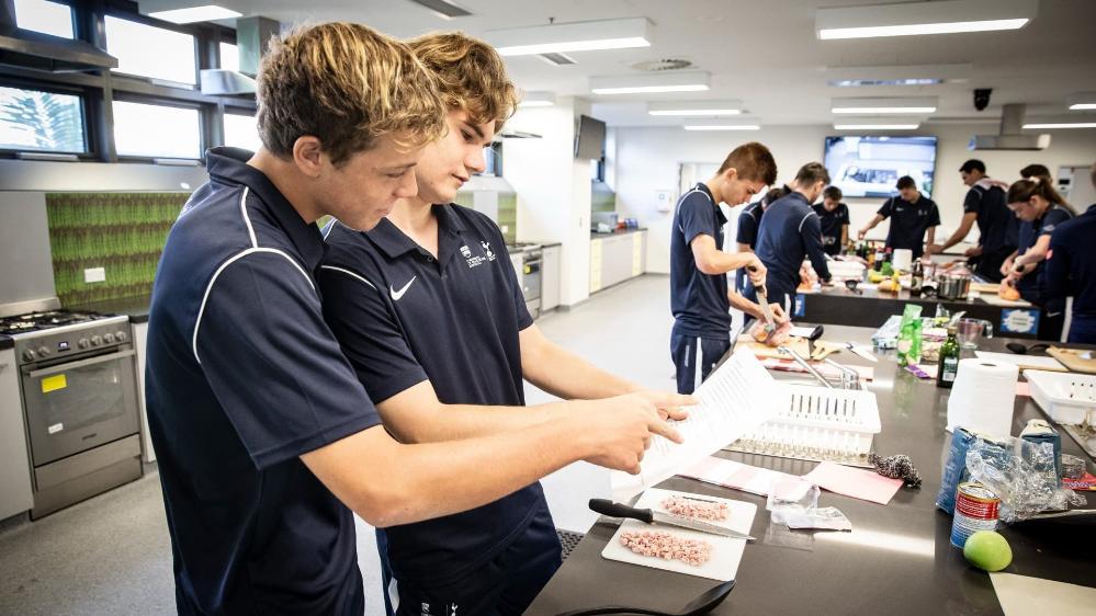 Two students chop bacon during a cooking lesson. Photo: Paul Jones