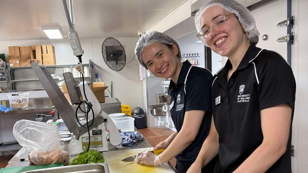 UOW nutrition and dietetics students Bing Lui and Eden Rothnie-White help with food preparation in the Meals on Wheels North Shoalhaven kitchen.