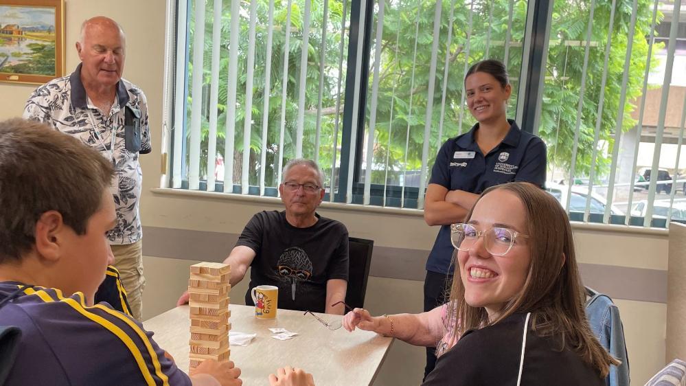 UOW students Natalie Rothnie and Eden Rothnie-White play a game of Jenga with Meals on Wheels clients and volunteers during the Meals Together luncheon in March 2025.