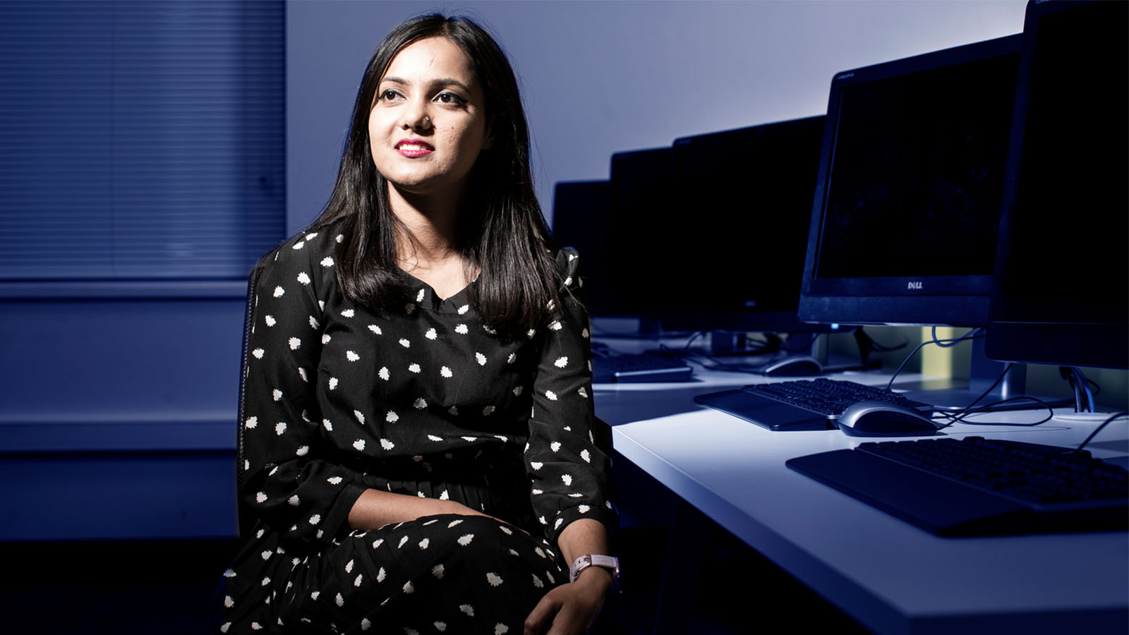 A woman is sitting at a computer desk looking to her left.