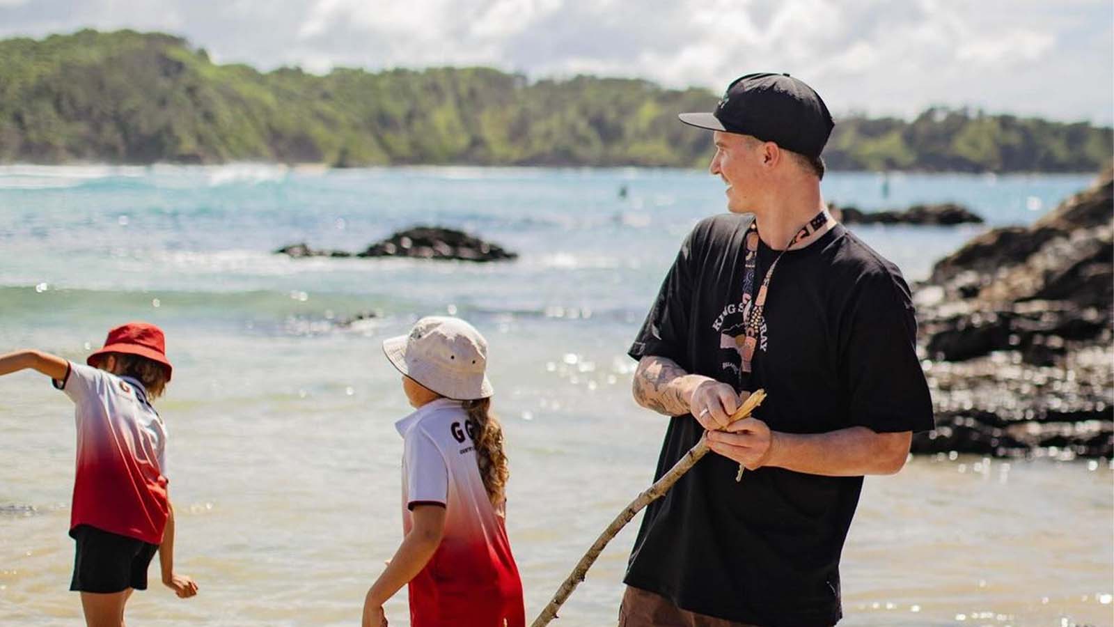 A man and two school children are on a beach